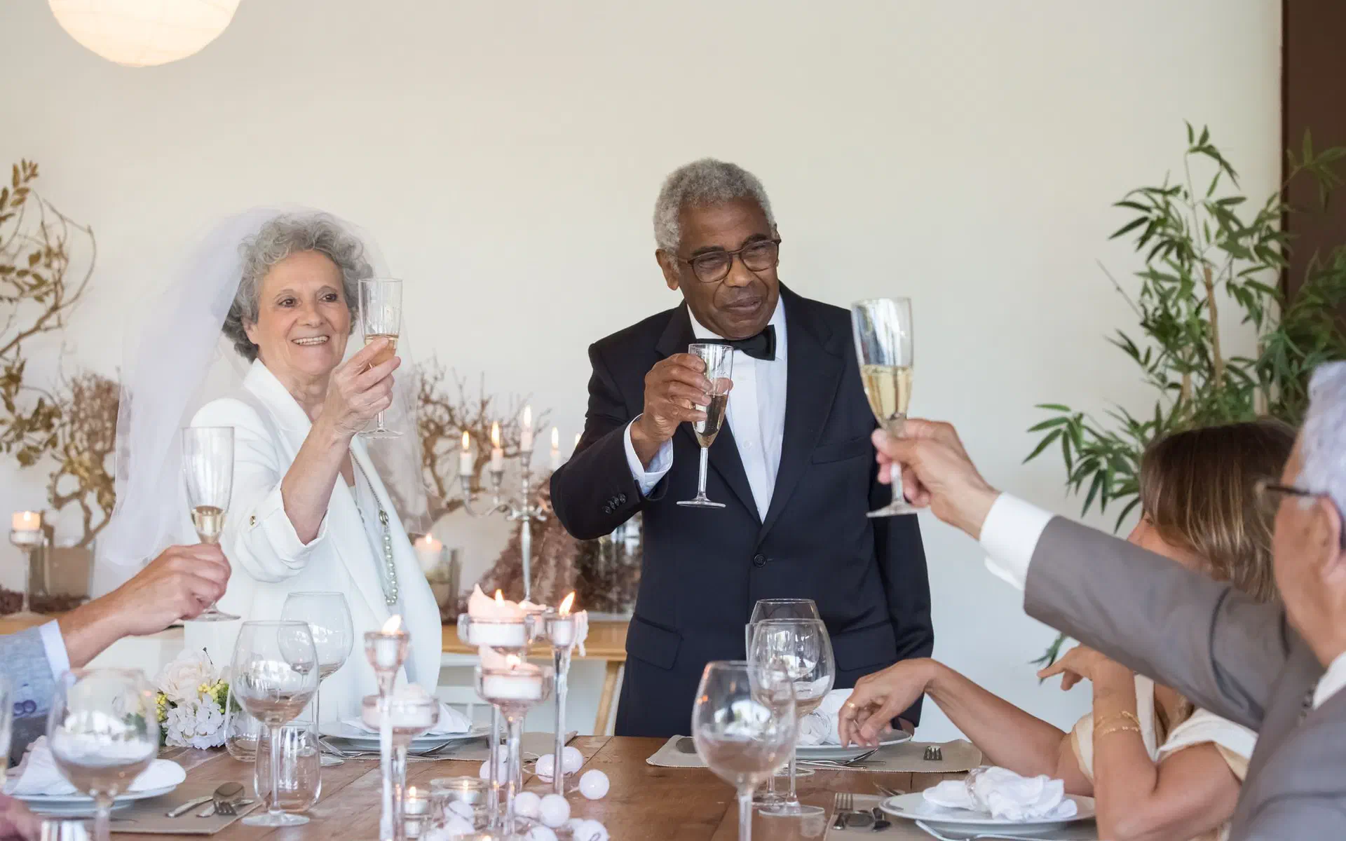 Noivos e convidados erguem as taças num brinde à mesa da festa de casamento
